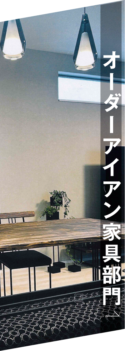 木製のテーブル、黒い椅子、ペンダントライト、小さな観葉植物が置かれたモダンな部屋。右側にはオーダーアイアン家具部門と書かれている。.