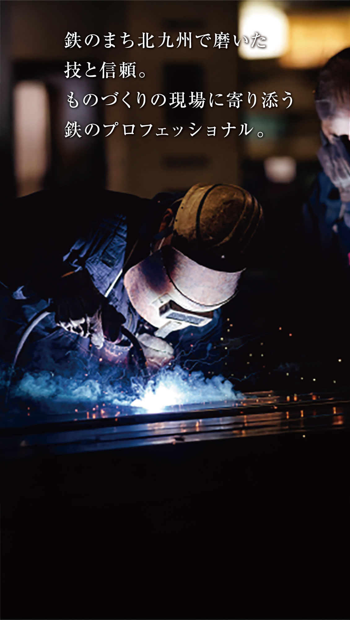 防護服を着た人が金属を溶接し、火花を散らしている。画像上部に日本語の文字が重なっている。.