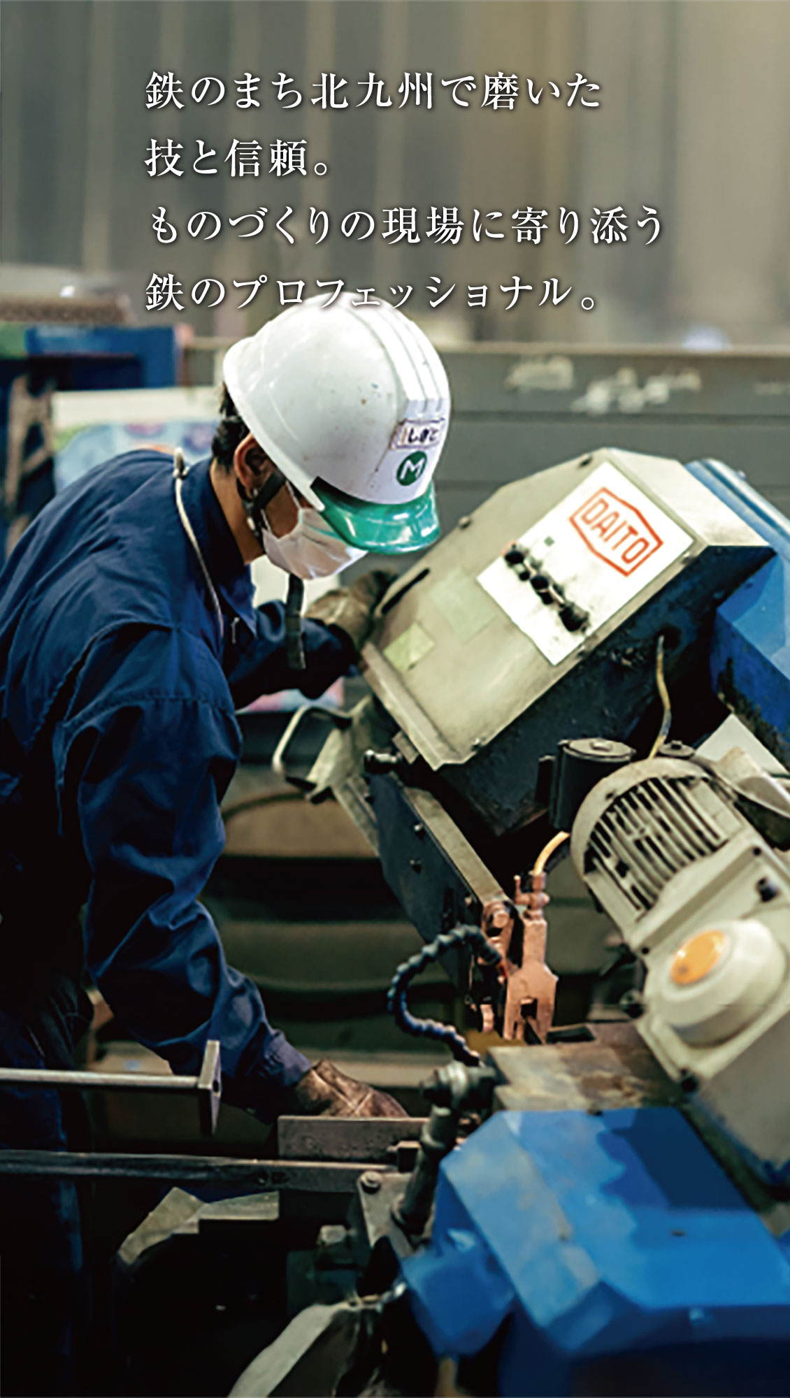 白い作業帽にマスク、安全眼鏡をかけた工場労働者が、作業場で青い産業機械を操作している。画像上部に日本語の文字が重なっている。.