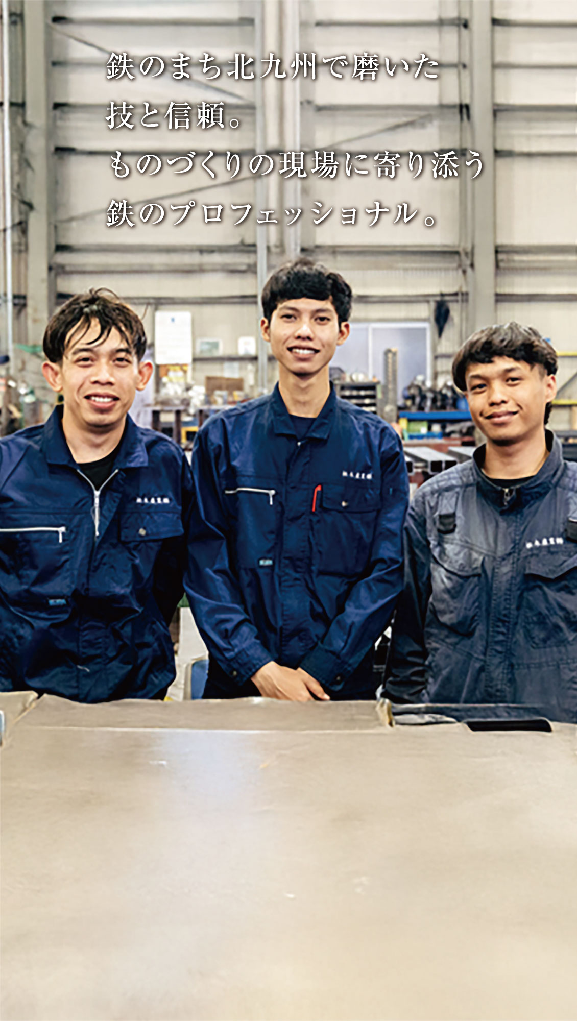 海軍の作業服を着た3人の青年が、工場内で並んで立っている。画像上部に日本語の文字が重なっている。背景には大きな金属板と設備が見える。.